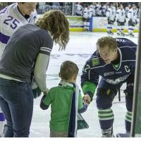 Maine Mariners defenseman Zach Tolkinen hands a puck to a young fan